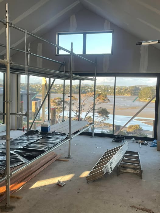 Scaffolded interior of a GV Homes architectural build in Raglan, vaulted gib ceiling, estuary view through floor-to-ceiling windows