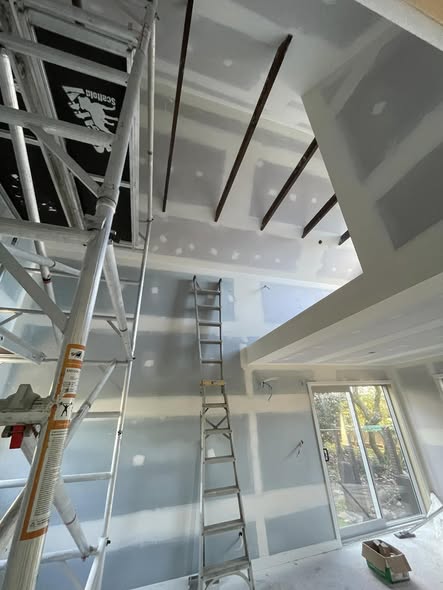 Living room mid-build with raw gib walls, scaffold tower and tools visible