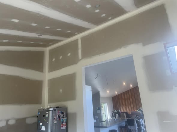 Interior under scaffolding with ladder, white-stopped ceiling and exposed rafter detail, garden view through sliding door
